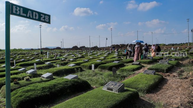 Warga melakukan ziarah kubur di Tempat Pemakaman Khusus Covid-19 TPU Rorotan, Jakarta Utara, Sabtu (22/4/2023). [Suara.com/Alfian Winanto]