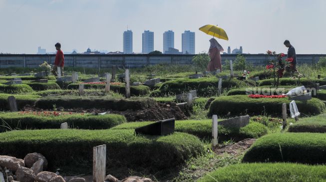 Warga melakukan ziarah kubur di Tempat Pemakaman Khusus Covid-19 TPU Rorotan, Jakarta Utara, Sabtu (22/4/2023). [Suara.com/Alfian Winanto]