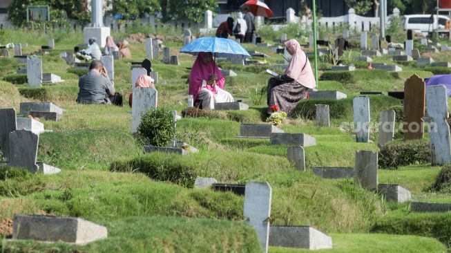 Warga berdoa saat melakukan ziarah kubur di Tempat Pemakaman Khusus Covid-19 TPU Rorotan, Jakarta Utara, Sabtu (22/4/2023). [Suara.com/Alfian Winanto]