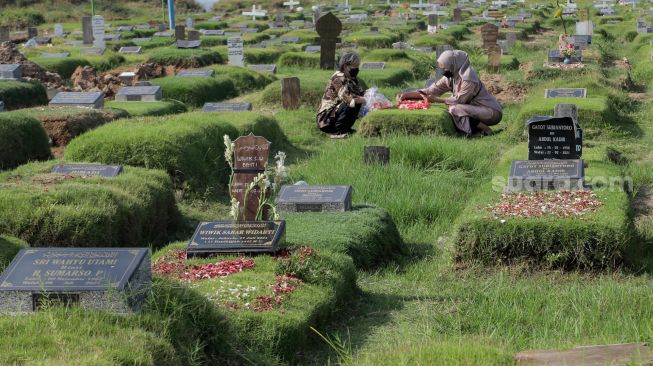 Warga berdoa saat melakukan ziarah kubur di Tempat Pemakaman Khusus Covid-19 TPU Rorotan, Jakarta Utara, Sabtu (22/4/2023). [Suara.com/Alfian Winanto]