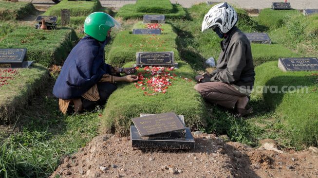 Warga berdoa saat melakukan ziarah kubur di Tempat Pemakaman Khusus Covid-19 TPU Rorotan, Jakarta Utara, Sabtu (22/4/2023). [Suara.com/Alfian Winanto]