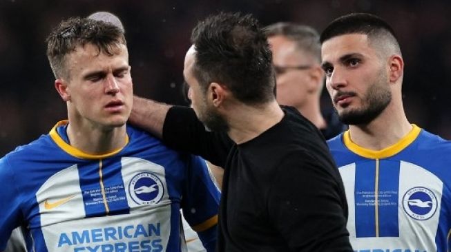 Pelatih Brighton Roberto De Zerbi menghibur Solly March (kiri) setelah pemainnya ini gagal mengeksekusi penalti dalam adu penalti selama pertandingan sepak bola semifinal Piala FA Inggris antara Manchester United dan Brighton dan Hove Albion di Stadion Wembley di London barat laut pada bulan April 23, 2023. Adrian DENNIS / AFP