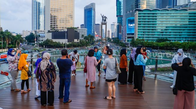 Warga berwisata di Anjungan Halte Transjakarta Bundaran HI, Jakarta Pusat, Kamis (27/4/2023). [Suara.com/Alfian Winanto]