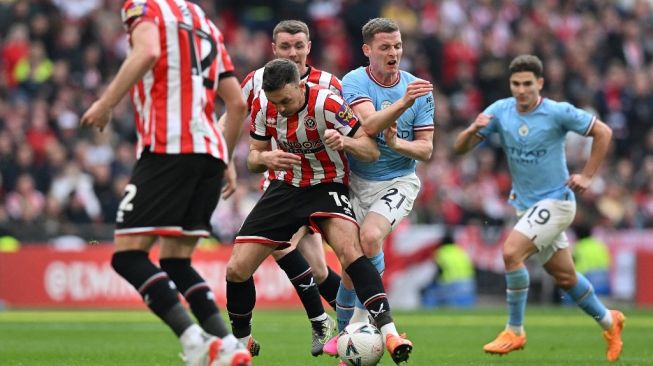 Bek Sheffield United Jack Robinson bentrok dengan bek Manchester City Sergio Gomez selama pertandingan semifinal Piala FA 2022-2023 antara Manchester City vs Sheffield United di Stadion Wembley di barat laut London pada 22 April 2023.Glyn KIRK / AFP.