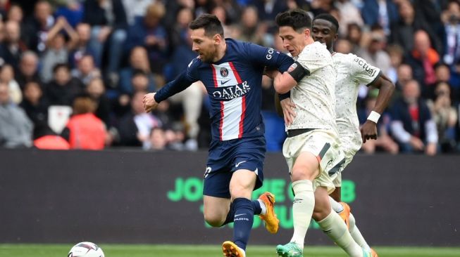 Penyerang Paris Saint-Germain (PSG) Lionel Messi (kiri) berebut bola dengan gelandang Prancis Laurent Abergel (kanan) selama pertandingan sepak bola Liga Prancis antara PSG vs FC Lorient di Stadion Parc des Princes di Paris pada 30 April 2023.FRANCK FIFE / AFP.