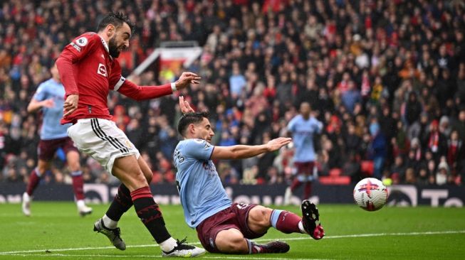 Gelandang Manchester United asal Portugal, Bruno Fernandes (kiri) melepaskan tembakkan yang menjadi gol pertama timnya selama pertandingan pekan ke-34 Liga Inggris 2022-2023 antara Manchester United vs Aston Villa di Old Trafford di Manchester, barat laut Inggris, pada 30 April 2023. Setan Merah menang 1-0.Oli SCARFF/AFP.