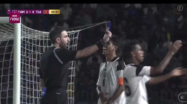 Pemain timnas Timor Leste U-22, Mouzinho (tengah) tertawa setelah wasit tidak menganggap aksi kiper timnas Kamboja U-22, Reth Lyheng yang menyentuh bola di luar kotak penalti sebagai pelanggaran dalam matchday perdana Grup A SEA Games 2023. [Soha.vn].