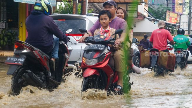 Warga melintasi banjir yang menggenangi Pondok Gede Permai, Bekasi, Jawa Barat, Kamis (4/5/2023). [Suara.com/Alfian Winanto]