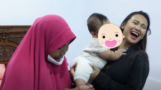 Momen bahagia Ibu Arie Kriting pakaikan gelang emas untuk sang cucu. (YouTube/ Indah Permatasari)