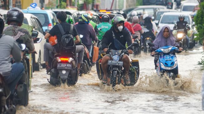 Warga melintasi banjir yang menggenangi Pondok Gede Permai, Bekasi, Jawa Barat, Kamis (4/5/2023). [Suara.com/Alfian Winanto]