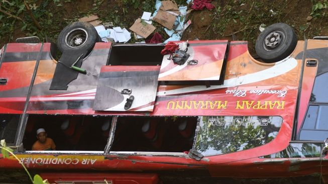 Seorang pria berada di sekitar bus pengangkut santri yang masuk ke jurang di kawasan Pegunungan Kebun Kopi di Parigi Moutong, Sulawesi Tengah, Kamis (4/5/2023). [ANTARA FOTO/Mohamad Hamzah].