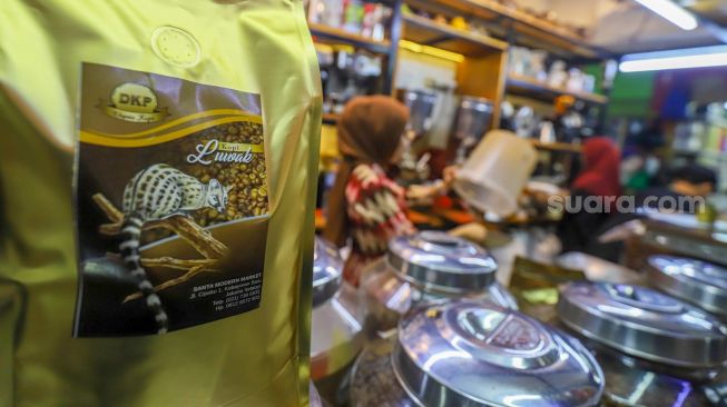 Pedagang memasukkan kopi ke dalam kemasan untuk pembeli di Dunia Kopi, Pasar Santa, Jakarta Selatan, Jumat (5/5/2023). [Suara.com/Alfian Winanto]