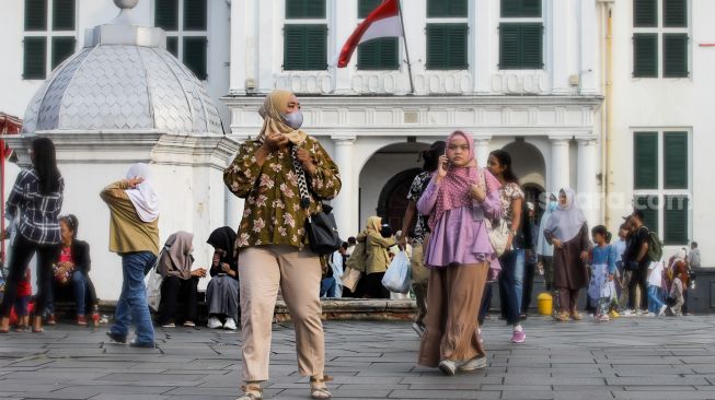Pengunjung memakai masker saat berwisata di Kawasan Kota Tua, Jakarta Barat, Sabtu (6/5/2023). [Suara.com/Alfian Winanto]