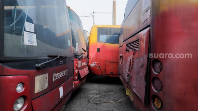 Deretan bus TransJakarta yang rusak dan tidak terawat terparkir di kawasan Terminal Terpadu Pulo Gebang, Jakarta Timur, Senin (15/5/2023). [Suara.com/Alfian Winanto]