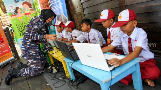 Seorang prajurit Kowal membimbing siswa mengoperasikan laptop di RPTRA Amiterdam saat peresmian Kampung Bahari Nusantara (KBN) di Pulau Untung Jawa, Kepulauan Seribu, Jakarta, Senin (15/5/2023). [ANTARA FOTO/M Risyal Hidayat/tom]