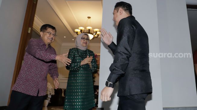 Wakil Presiden Indonesia ke-10 dan ke-12 Jusuf Kalla (kiri) ditemani istrinya Mufidah Jusuf Kalla (kedua kiri) menyambut kedatang Ketua Umum Partai Demokrat Agus Harimurti Yudhoyono (kanan) saat menggelar pertemuan di Jalan Brawijaya, Jakarta Selatan, Senin (15/5/2023). [Suara.com/Alfian Winanto]