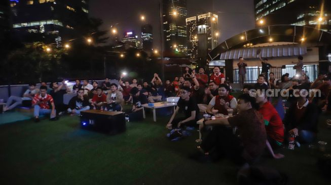 Sejumlah warga menyaksikan pertandingan final cabang olahraga sepak bola antara Indonesia melawan Thailand di Green Cafe Semanggi, Jakarta, Selasa (16/5/2023). [Suara.com/Alfian Winanto]