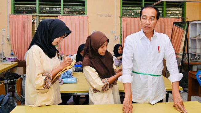 Seorang siswi SMKN 4 Kota Jambi tengah mengukur tubuh Presiden Joko Widodo atau Jokowi untuk dibuatkan sebuah pakaian, Selasa (16/5/2023). (Laily Rachev - Biro Pers Sekretariat Presiden)