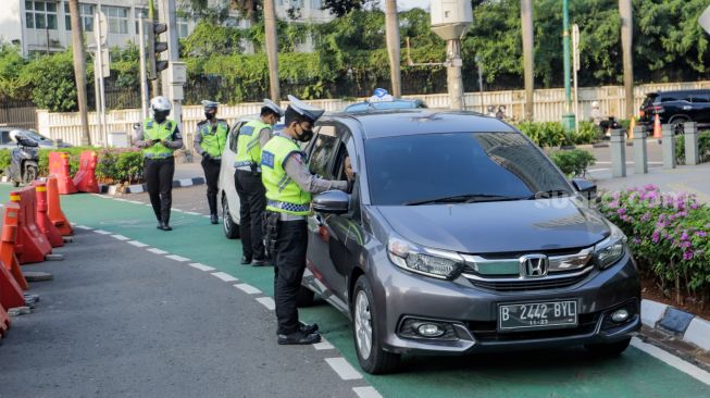 Petugas Kepolisian melakukan penindakan tilang manual terhadap pengemudi di kawasan Bundaran Hotel Indonesia, Jakarta, Selasa (16/5/2023). [Suara.com/Alfian Winanto]