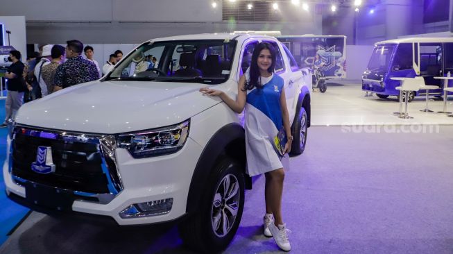 Model berpose di dekat mobil listrik E-Double Cabin milik PT Mobil Anak Bangsa (MAB) yang dipamerkan pada Periklindo Electric Vehicle Show (PEVS) 2023 di JIExpo Kemayoran, Jakarta, Rabu (17/5/2023). [Suara.com/Alfian Winanto]