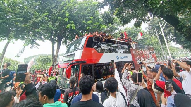 Para pemain Timnas Indonesia U-22 menaiki bus untuk mengikuti arak-arakan setelah merebut medali emas cabang olahraga (cabor) sepak bola putra SEA Games 2023. Arak-arakan dimulai di kantor Kemenpora, Senayan, Jakarta pada Jumat (19/5/2023) mulai pukul 08.00 WIB. [Adie Prasetyo Nugraha/Suara.com]