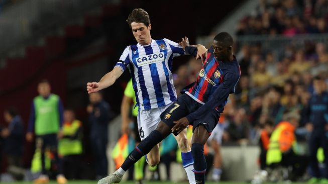 Bek Real Sociedad asal Spanyol Aritz Elustondo (kiri) berebut bola dengan penyerang Barcelona asal Prancis Ousmane Dembele selama pertandingan pekan ke-35 Liga Spanyol 2022-2023 antara FC Barcelona vs Real Sociedad di stadion Camp Nou di Barcelona pada 20 Mei 2023.Lluis GEN / AFP.