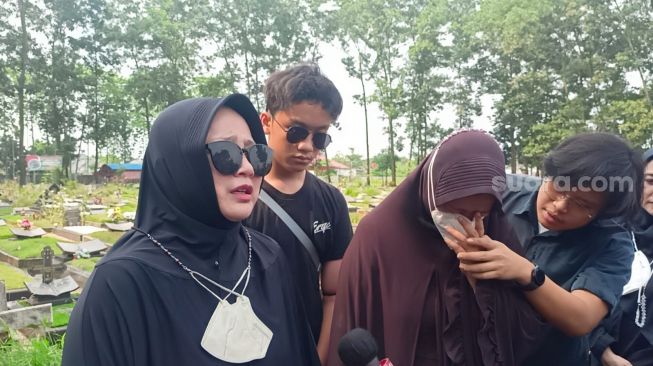 Feni, keponakan Eeng Saptahadi (jilbab hitam) bersama Yani (jilbab Coklat) di TPU Cipenjo, Cileungsi, Bogor Jawa Barat pada Senin (22/5/2023) [Suara.com/Rena Pangesti]