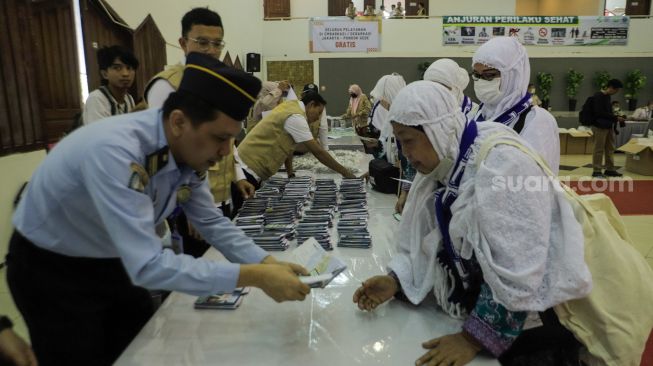 Petugas melakukan pengecekan paspor jamaah calon haji lansia embarkasi Jakarta di Asrama Haji Pondok Gede, Jakarta, Selasa (23/5/2023). [Suara.com/Alfian Winanto]
