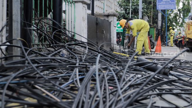 Petugas Dinas Bina Marga DKI Jakarta melakukan penataan kabel utilitas di sekitar Jalan Haji Agus Salim, Jakarta Pusat, Rabu (24/5/2023). [Suara.com/Alfian Winanto]