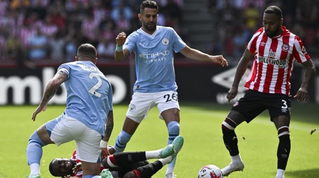 Bek Manchester City Kyle Walker (Kiri) melakukan pelanggaran terhadap gelandang Brentford Frank Onyeka (bawah) di samping gelandang Manchester City Riyad Mahrez (belakang tengah) dan bek Brentford Rico Henry (kanan) selama pertandingan pekan ke-38 Liga Inggris 2022-2023 antara Brentford vs Manchester City di Gtech Community Stadium di London pada 28 Mei 2023.Ben Stansall / AFP.