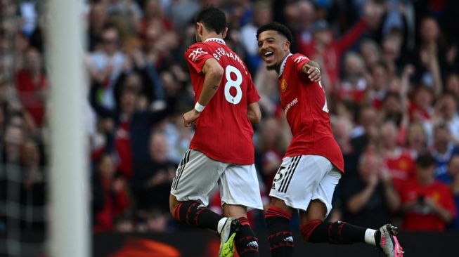 Gelandang Manchester United, Bruno Fernandes (kiri) melakukan selebrasi usai mencetak gol ke gawang Fulham bersama winger Jadon Sancho, dalam laga Liga Inggris di Old Trafford, Senin (29/5/2023) dini hari WIB. [PAUL ELLIS / AFP]