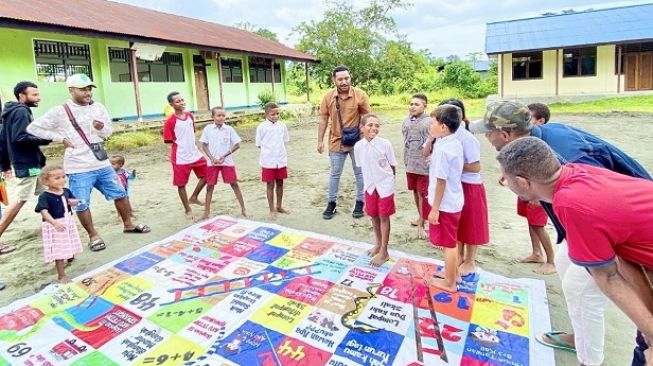 Para relawan Papua Future Project mengajak anak-anak belajar dengan menggunakan permainan ular tangga agar pelajaran yang diberikan tidak terasa membebani anak-anak di sana [Astra].