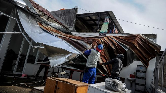 Warga memperbaiki atap rumah yang rusak diterjang angin puting beliung di Bojong Malaka, Baleendah, Kabupaten Bandung, Jawa Barat, Rabu (7/62023). [ANTARA FOTO/Raisan Al Farisi]