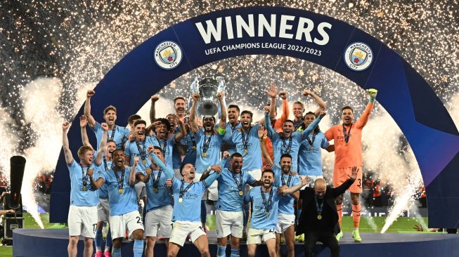 Kapten Manchester City Ilkay gundogan (Tengah) bersama para pemain lainnya mengangkat trofi Piala Liga Champions untuk merayakan kemenangan mereka dalam pertandingan sepak bola final Liga Champions antara Inter Milan dan Manchester City di Stadion Olimpiade Ataturk di Istanbul, Turki, Sabtu (10/6/2023). [Paul ELLIS / AFP]