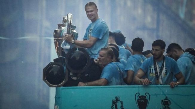 Striker Manchester City Erling Haaland memegang Piala Eropa saat ia merayakan bersama rekan setimnya tiga trofi termasuk Piala FA dan Liga Premier selama parade kemenangan bus atap terbuka di jalan-jalan Manchester, Inggris utara pada 12 Juni 2023. Paul ELLIS / AFP