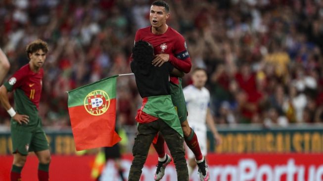 Seorang pendukung menerobos lapangan dan mengangkat striker timnas Portugal Cristiano Ronaldo selama pertandingan kualifikasi Grup J EURO 2024 antara Portugal vs Bosnia-Herzegovina di stadion Luz di Lisbon pada 17 Juni 2023.CARLOS COSTA / AFP.