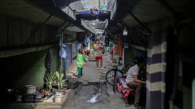 Sejumlah warga berdiri di kawasan permukiman di bawah jalan tol dalam kota Cawang-Tomang-Pluit di Jelambar Baru, Jakarta Barat, Selasa (20/6/2023). [ANTARA FOTO/Fauzan].