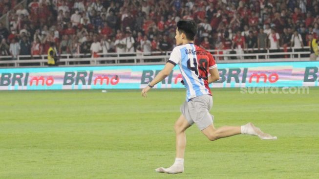 Seorang suporter mengenakan jersey Timnas Indonesia dan Argentina masuk ke dalam lapangan Stadion Utama Gelora Bung Karno (SUGBK), Senayan, Jakarta, Senin (19/6/2023) malam. [Suara.com/Dwi Bowo Raharjo]