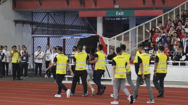 Seorang suporter mengenakan jersey Timnas Indonesia dan Argentina diamankan usai masuk ke dalam lapangan Stadion Utama Gelora Bung Karno (SUGBK), Senayan, Jakarta, Senin (19/6/2023). [Suara.com/Dwi Bowo Raharjo]