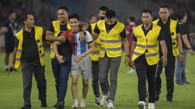 Pengaman pertandingan mengamankan seorang suporter yang memasuki lapangan saat pertandingan FIFA Matchday antara Timnas Indonesia melawan Timnas Argentina di Stadion Utama Gelora Bung Karno, Jakarta, Senin (19/6/2023). Timnas Indonesia kalah dari timnas Argentina dengan skor 0-2. ANTARA FOTO/Galih Pradipta/tom.