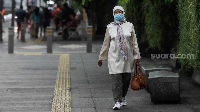 Pejalan kaki memakai masker saat melintas di Kawasan Bundaran HI, Jakarta, Rabu (21/6/2023). [Suara.com/Alfian Winanto]