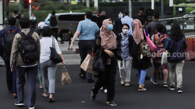 Pejalan kaki memakai masker saat melintas di Kawasan Bundaran HI, Jakarta, Rabu (21/6/2023). [Suara.com/Alfian Winanto]