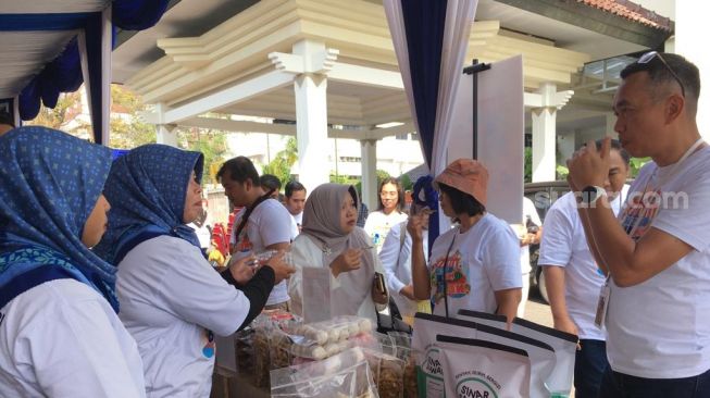 Regional CEO Bank Rakyat Indonesia (BRI) Yogyakarta, John Sarjono saat merasakan kripik belut Sinar Sawah di event Bazaar UMKM BRILian di Kantor BRI Cik di Tiro Yogyakarta, Jumat (16/6/2023) [Suara.comHadi]