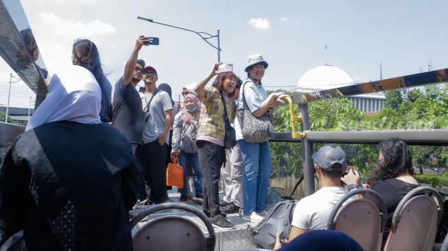 Warga saat menaiki Bus Wisata Transjakarta dengan atap terbuka di Jakarta, Rabu (28/6/2023). [Suara.com/Alfian Winanto]
