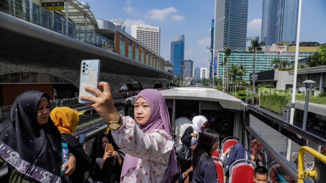 Warga saat menaiki Bus Wisata Transjakarta dengan atap terbuka di Jakarta, Rabu (28/6/2023). [Suara.com/Alfian Winanto]
