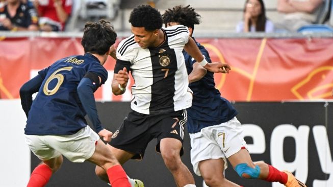 Penyerang timnas Jerman U-17 Paris Brunner (tengah) dan gelandang Prancis Nolan Ferro (kiri) berebut bola selama pertandingan final Euro U-17 antara Jerman vs Prancis di Stadion Hidegkuti Nandor di Budapest, Hongaria pada 2 Juni 2023.Attila KISBENEDEK/AFP.