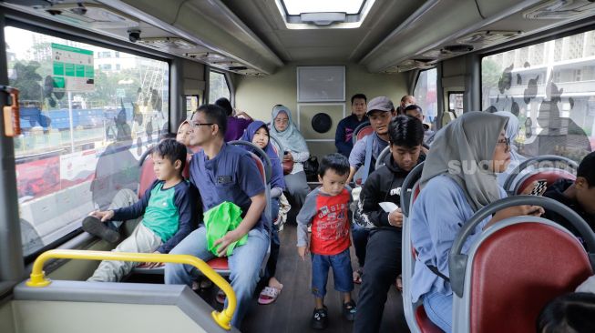 Warga saat menaiki Bus Wisata Transjakarta dengan atap terbuka di Jakarta, Rabu (28/6/2023). [Suara.com/Alfian Winanto]
