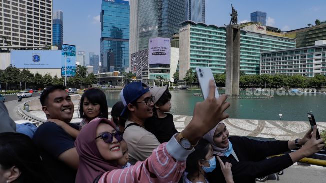 Warga saat menaiki Bus Wisata Transjakarta dengan atap terbuka di Jakarta, Rabu (28/6/2023). [Suara.com/Alfian Winanto]
