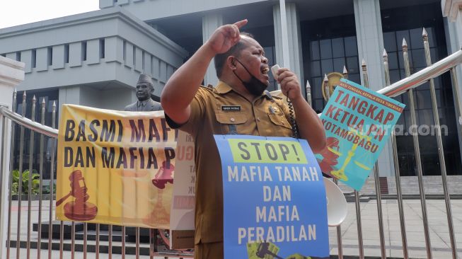 Kepala Desa Tiberias, Abner Patras saat menggelar aksi demo tunggal di depan Gedung Mahkamah Agung RI, Jakarta Pusat, Rabu (5/7/2023). [Suara.com/Alfian Winanto]