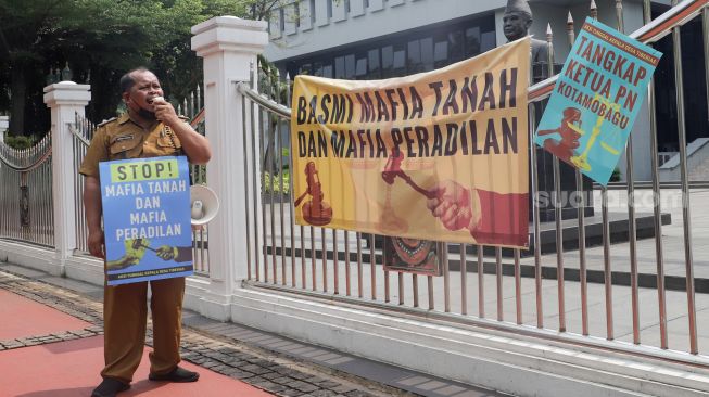 Kepala Desa Tiberias, Abner Patras saat menggelar aksi demo tunggal di depan Gedung Mahkamah Agung RI, Jakarta Pusat, Rabu (5/7/2023). [Suara.com/Alfian Winanto]